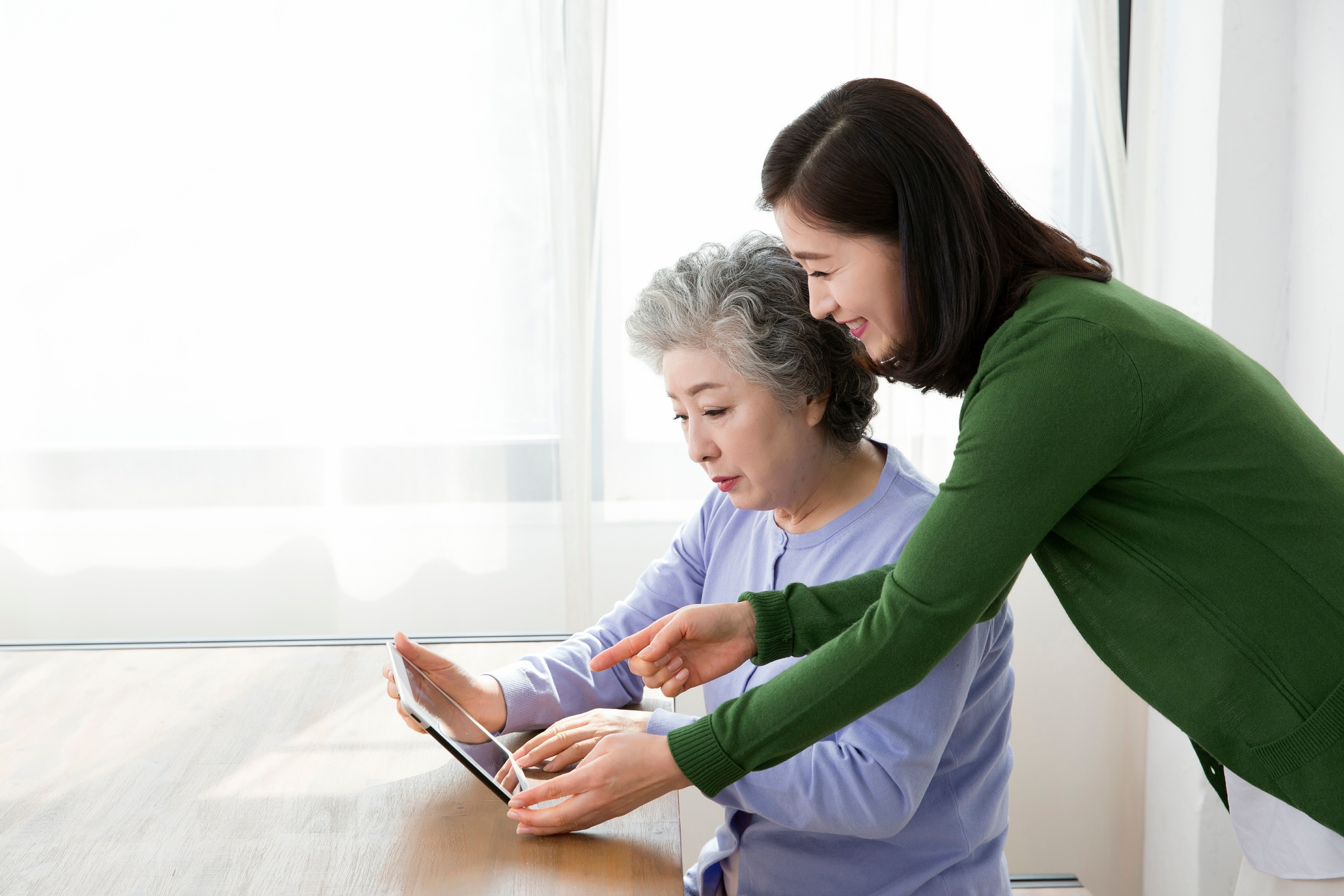Older woman and family member using a tablet together at home