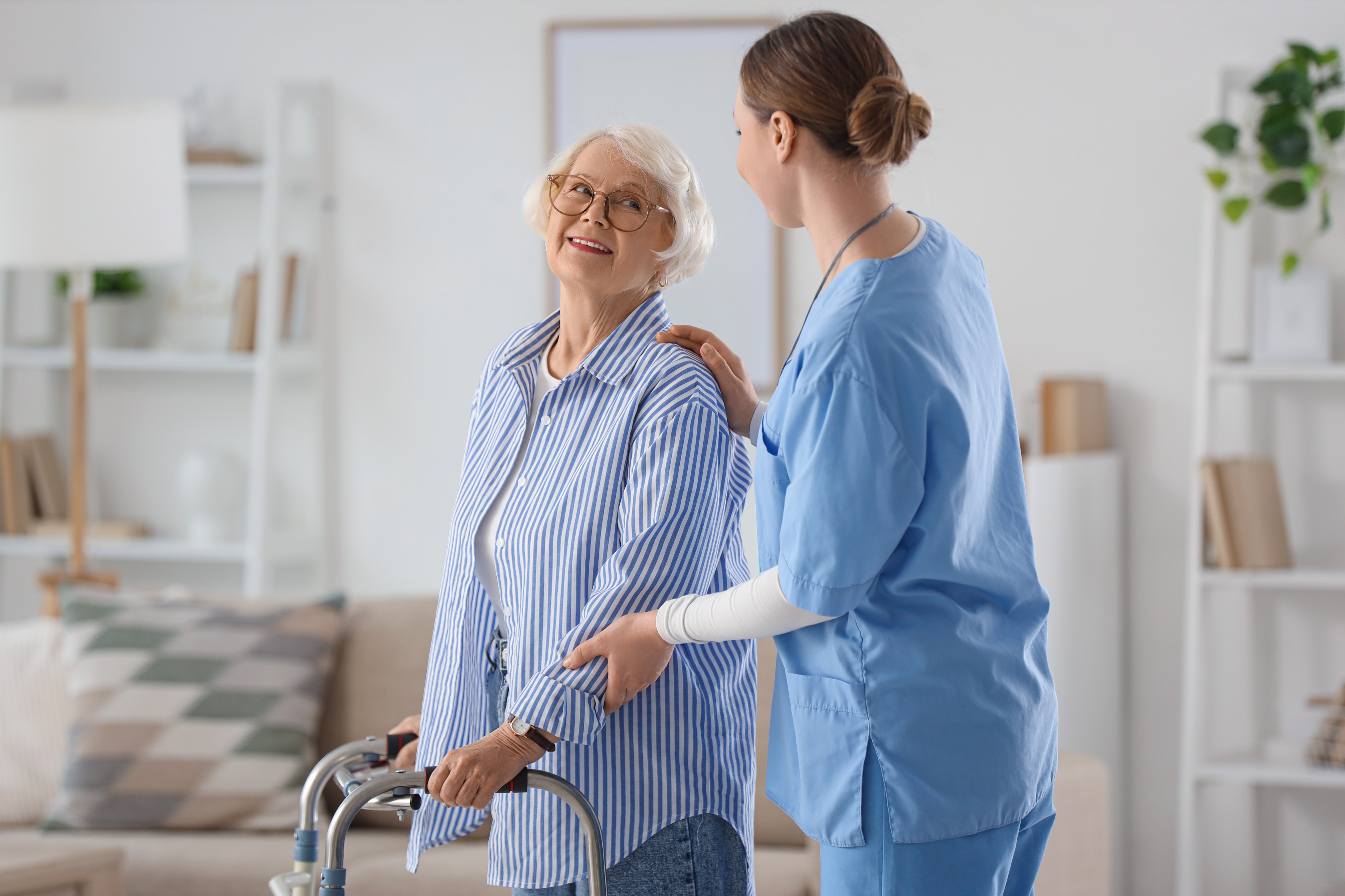 Care worker supporting an older woman with a walker